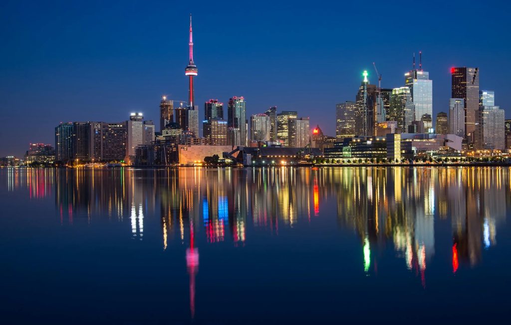 Stunning night view of Toronto skyline reflecting on water with CN Tower prominent.